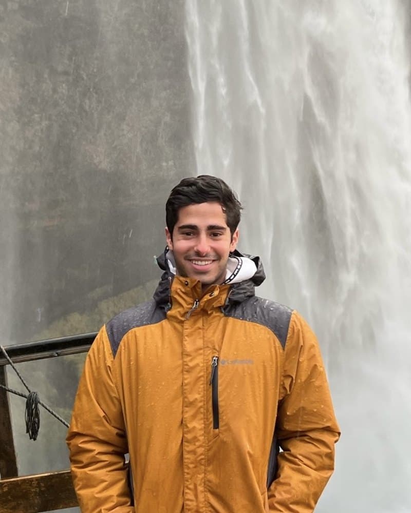 Marcos, who roasts for Floresco, standing in front of a waterfall